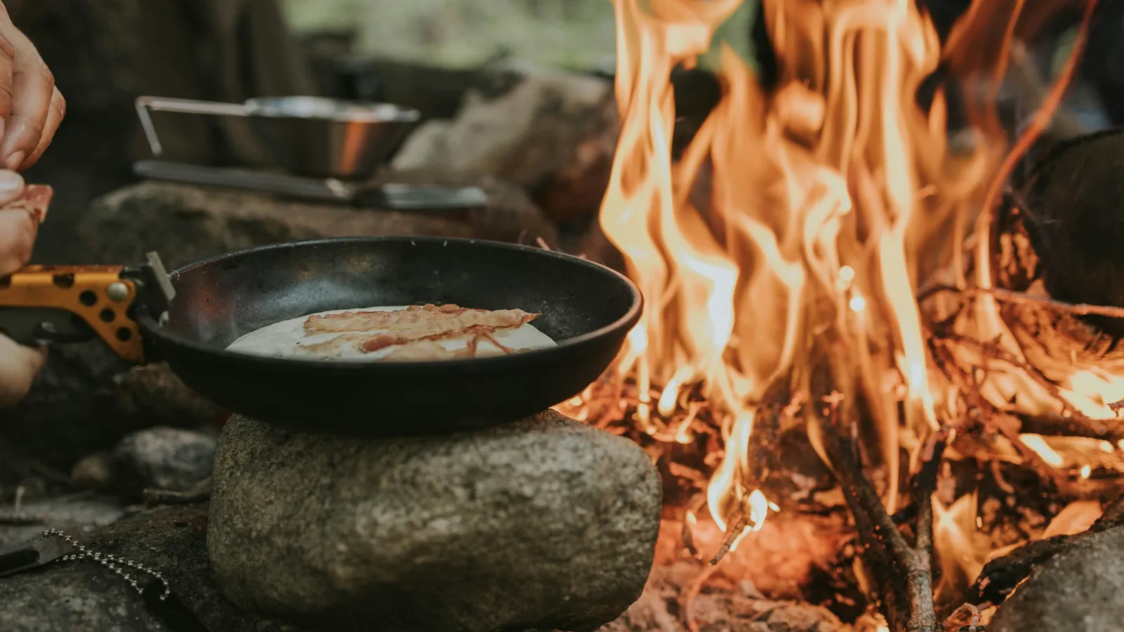 Breakfast cooking in a cast iron skillet over a campfire