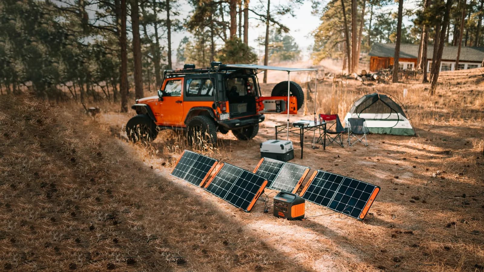 A tent pitched at a forest campsite with a portable power station and camp chairs