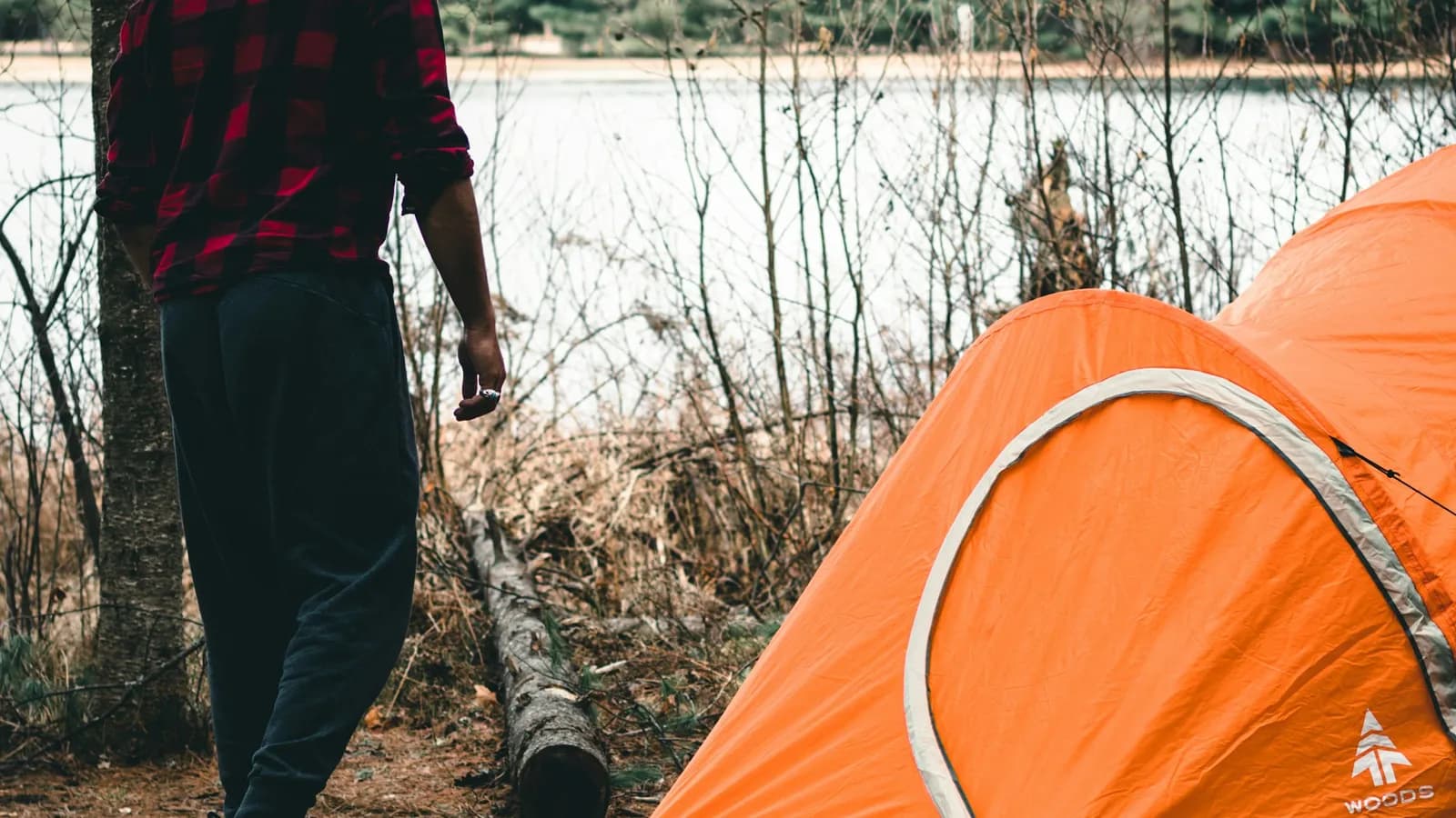 Camper standing next to a tent at a campsite