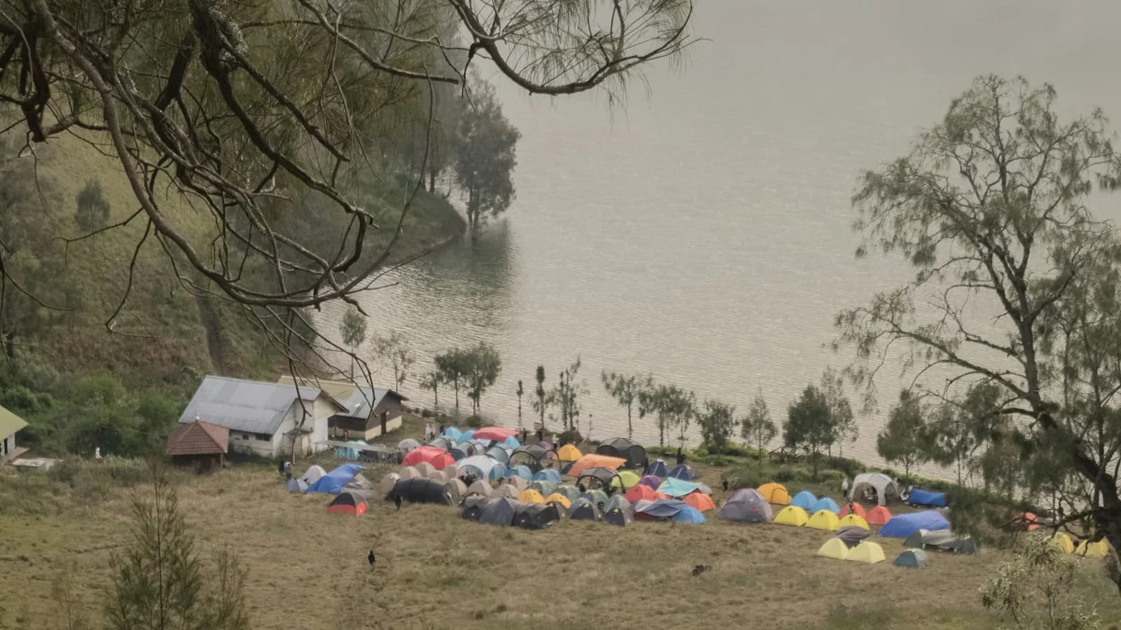Colorful tents pitched beside a misty mountain lake