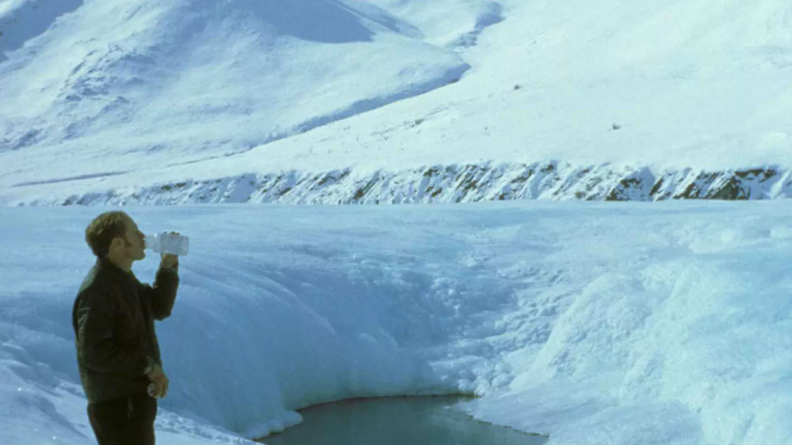 A hiker drinks water during a mountain rest